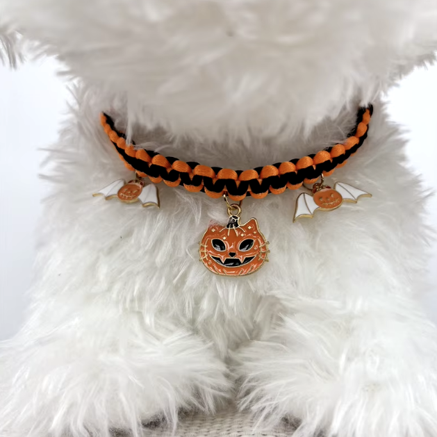 Cat wearing a Halloween breakaway collar with a small pumpkin pendant and festive woven design.