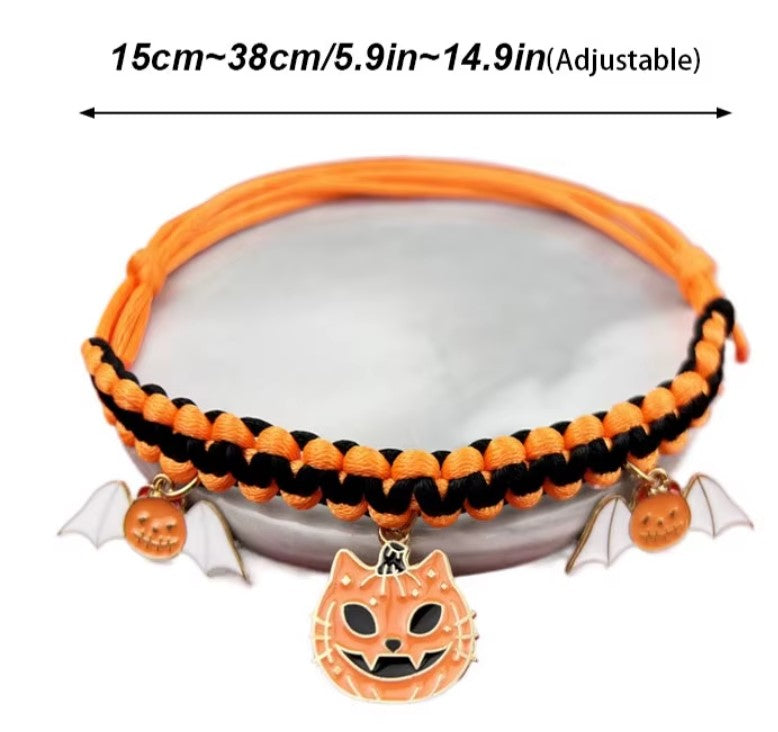 Cat wearing a Halloween breakaway collar with a small pumpkin pendant and festive woven design.