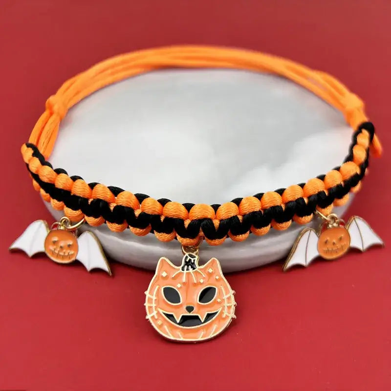Cat wearing a Halloween breakaway collar with a small pumpkin pendant and festive woven design.