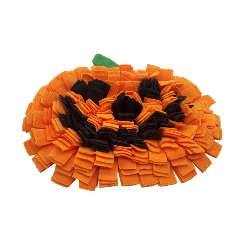 Dog sniffing a Halloween-themed pumpkin snuffle mat for hidden treats.