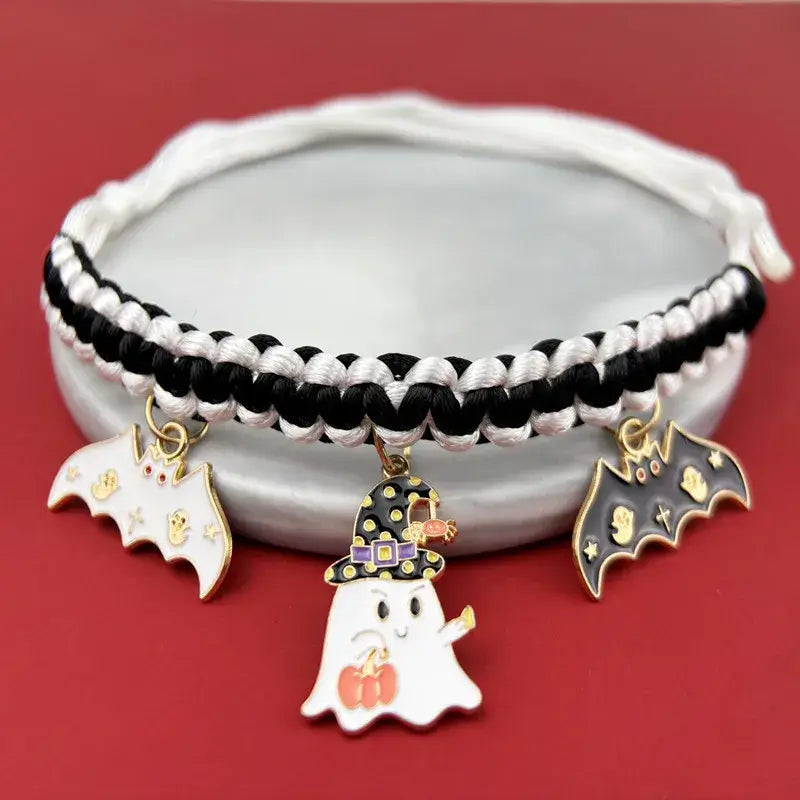 Cat wearing a Halloween breakaway collar with a small pumpkin pendant and festive woven design.