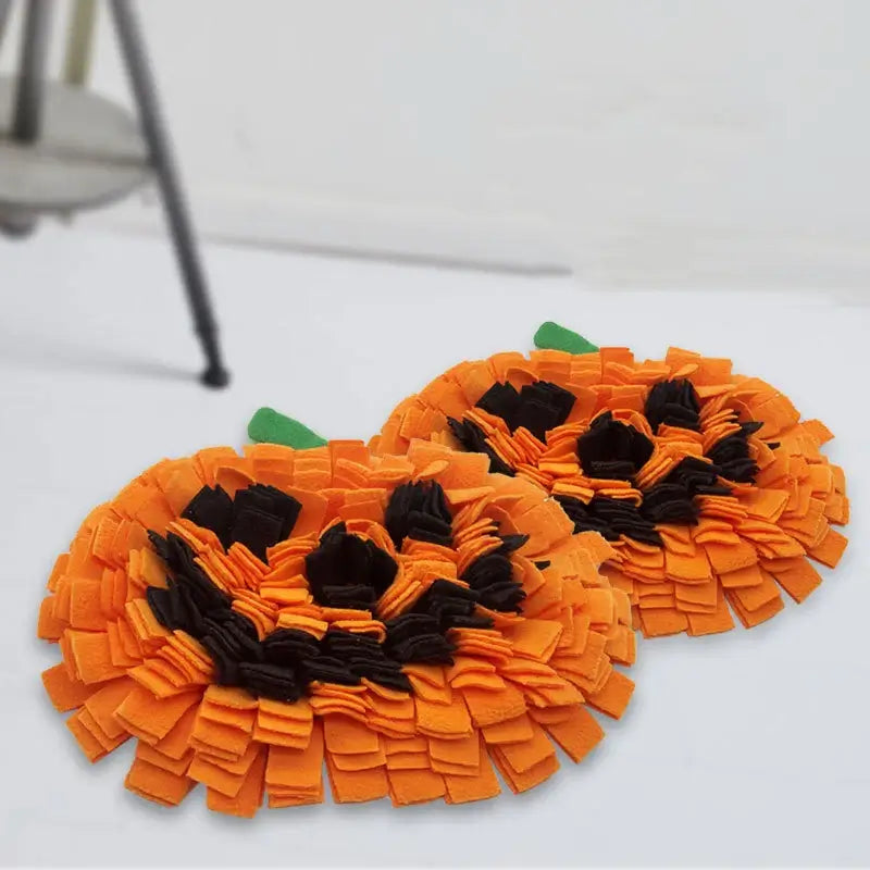 Dog sniffing a Halloween-themed pumpkin snuffle mat for hidden treats.