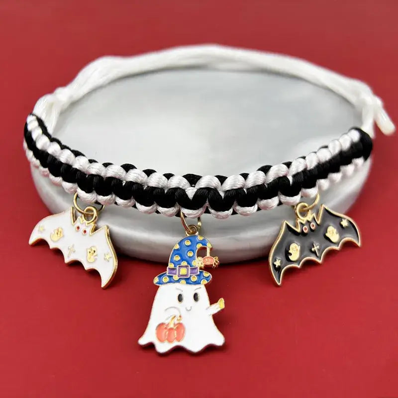 Cat wearing a Halloween breakaway collar with a small pumpkin pendant and festive woven design.